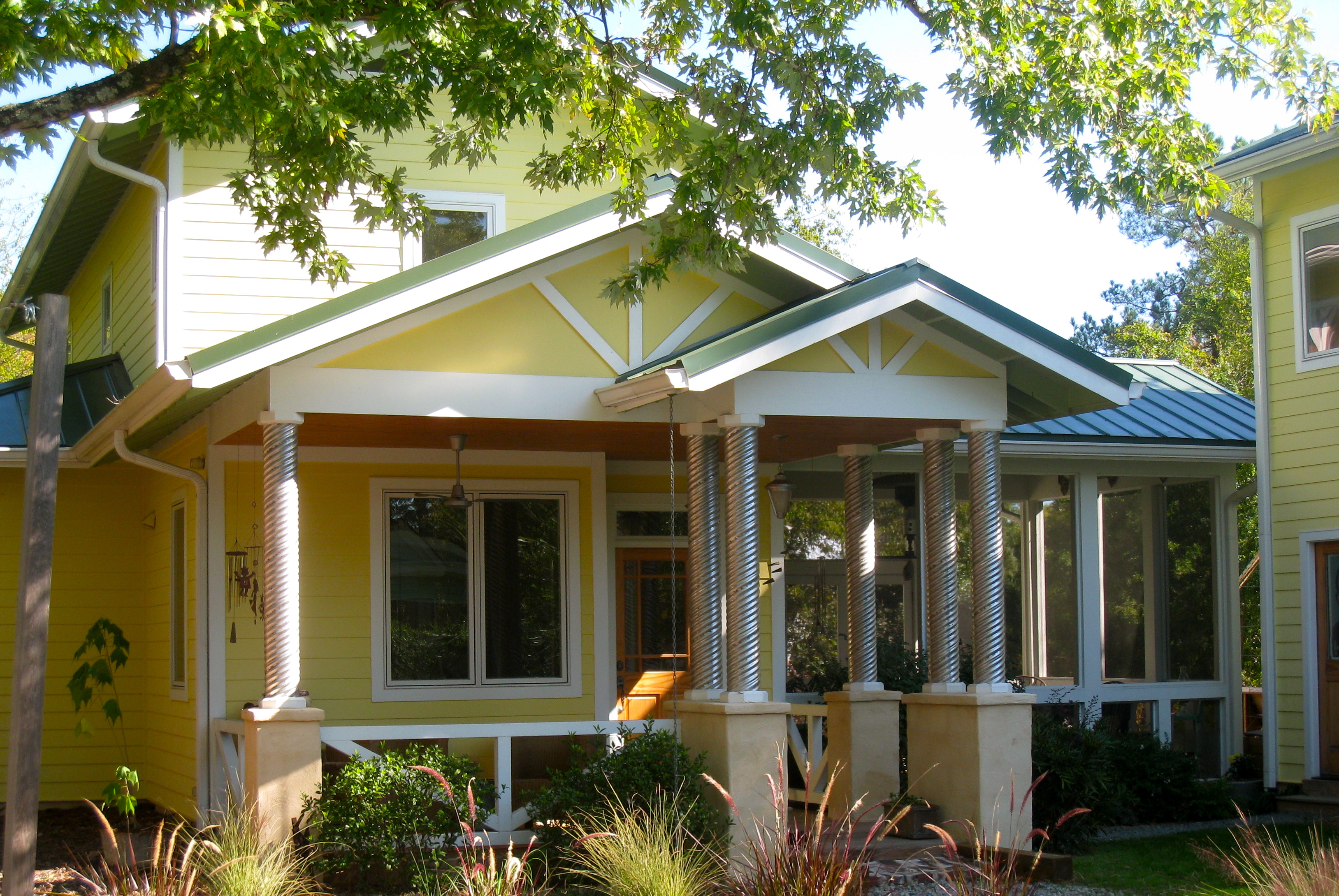 Unique yellow wood home with white trim and metal bannisters